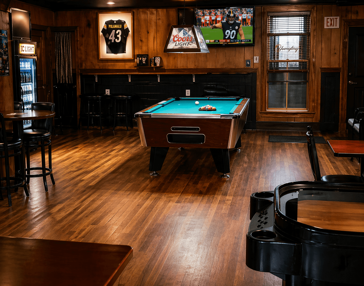 BoRocks pool table room with wood floor, bar seating, Steelers decor, and TVs